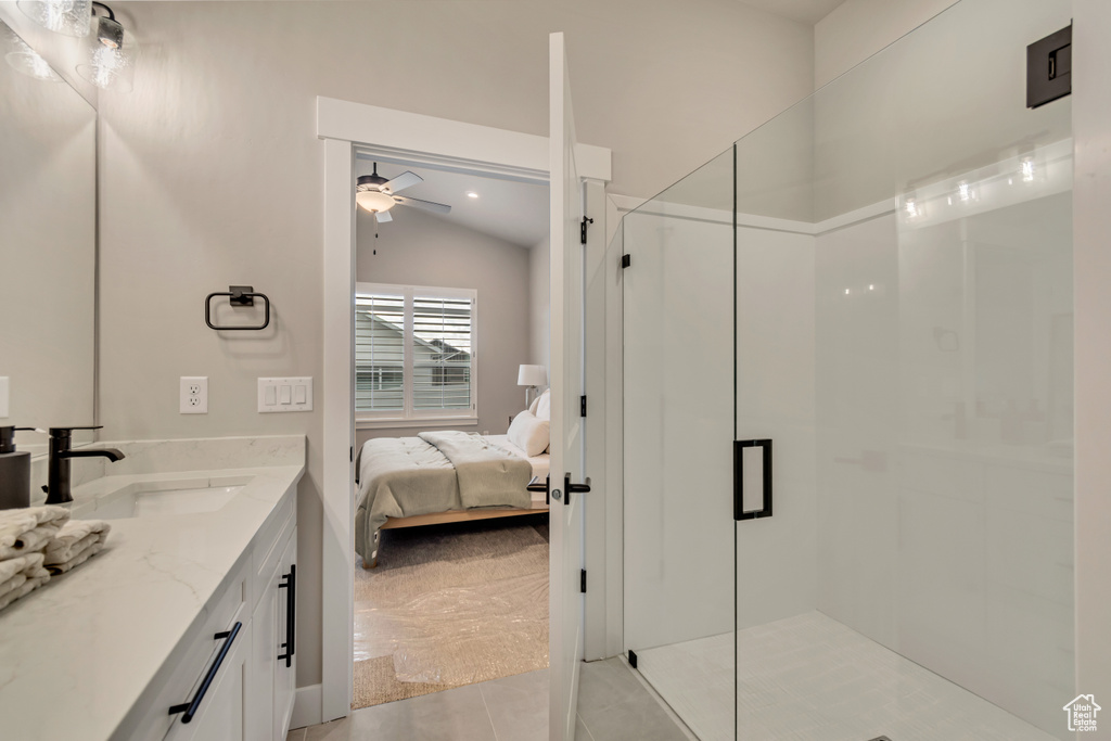 Bathroom featuring tile patterned floors, vaulted ceiling, ceiling fan, vanity, and a stall shower