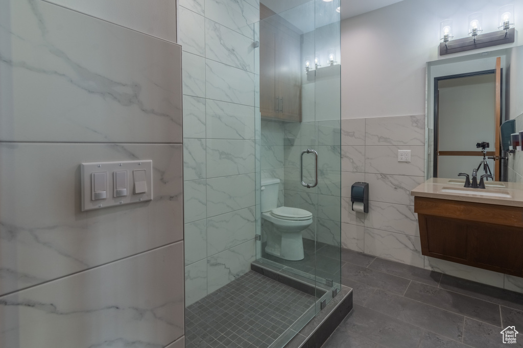 Bathroom featuring vanity, an enclosed shower, tile walls, and toilet