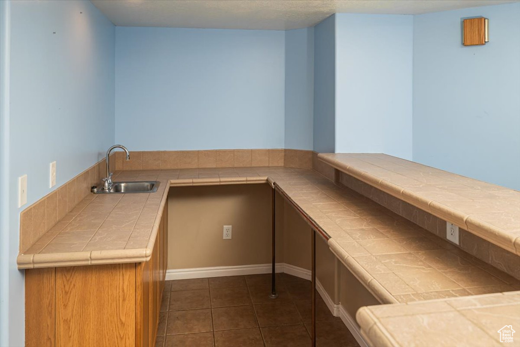 Interior space featuring tile countertops, sink, and dark tile patterned flooring