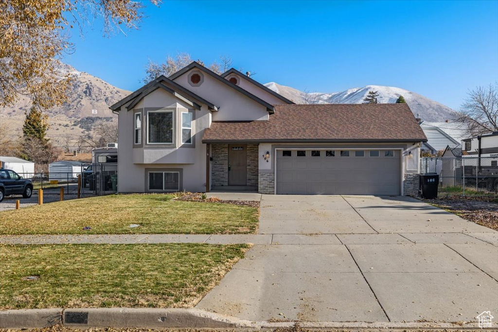 View of front of home with a mountain view, a garage, and a front lawn