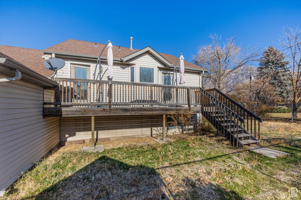 Back of property featuring a lawn and a deck