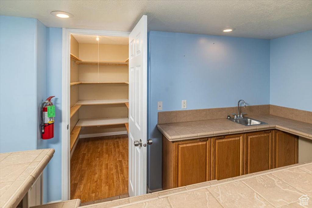 Kitchen with hardwood / wood-style floors, a textured ceiling, tile countertops, and sink