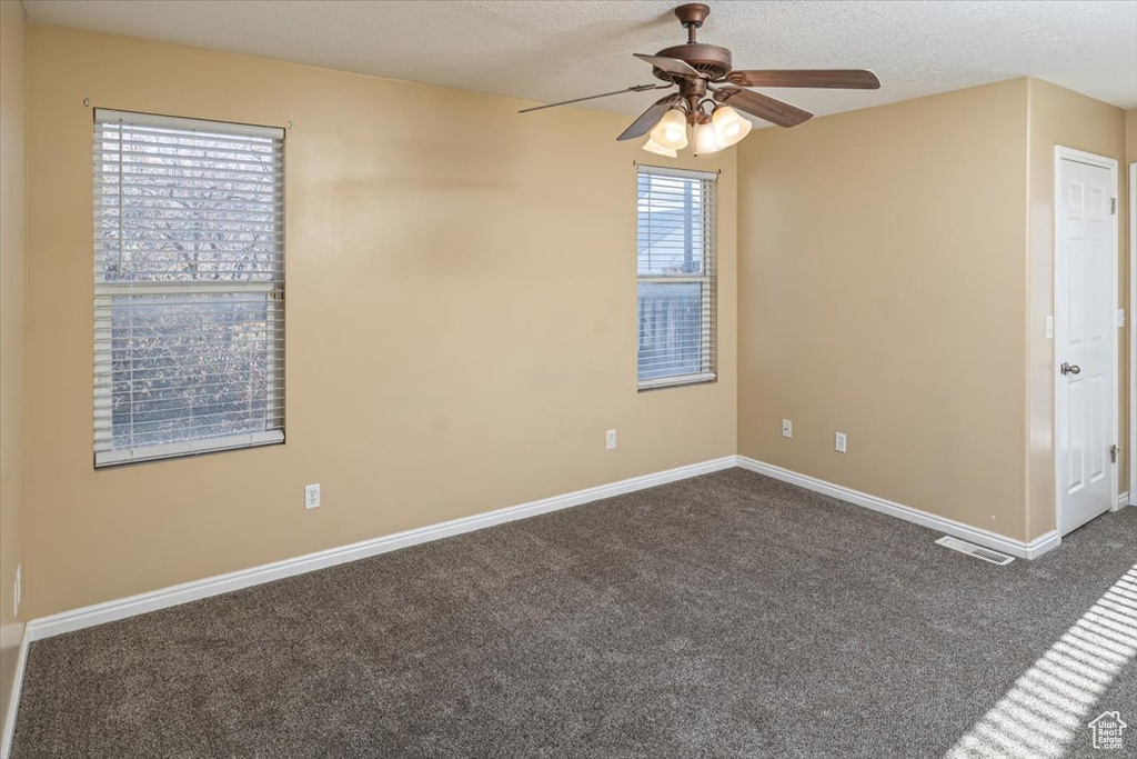 Carpeted empty room featuring ceiling fan and a textured ceiling