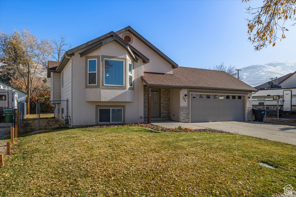 View of front of property with a mountain view, a garage, and a front lawn