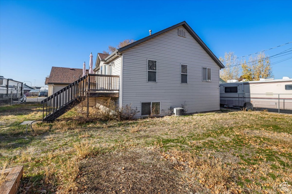 Back of house featuring a yard and central AC