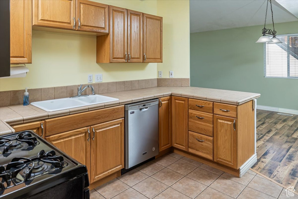 Kitchen with sink, decorative light fixtures, black range, dishwasher, and light hardwood / wood-style floors