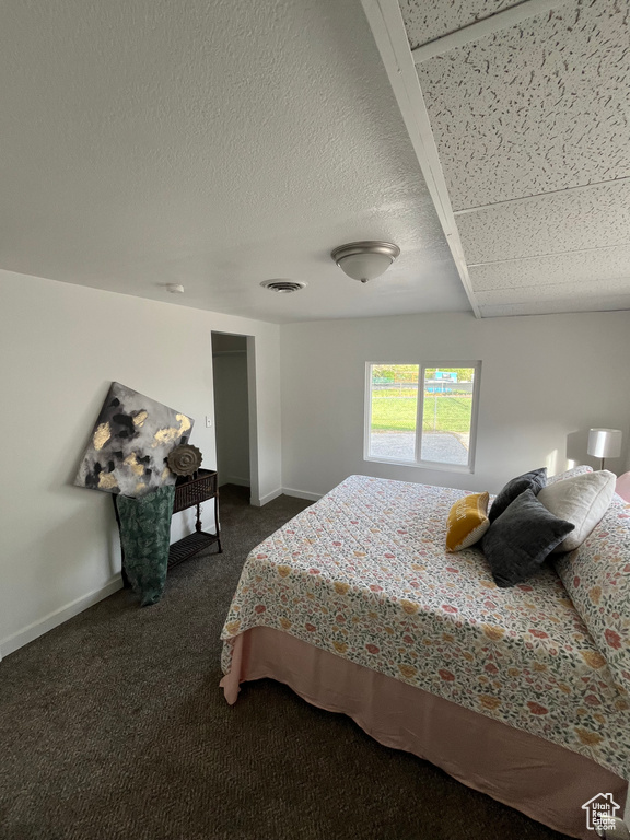 Bedroom with dark carpet, visible vents, and baseboards
