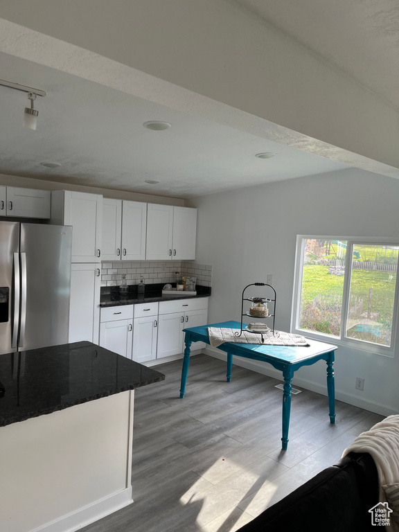 Interior space with rail lighting, wood finished floors, and baseboards