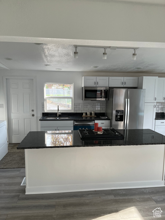 Kitchen with dark countertops, appliances with stainless steel finishes, and a sink