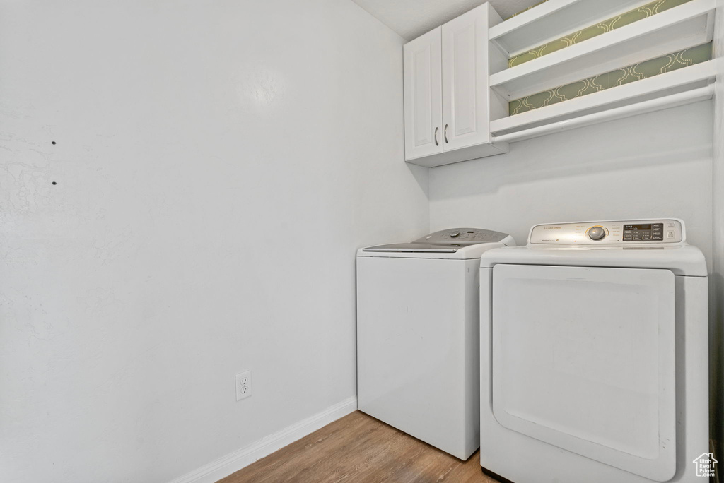 Laundry room featuring cabinets, light wood-type flooring, and separate washer and dryer