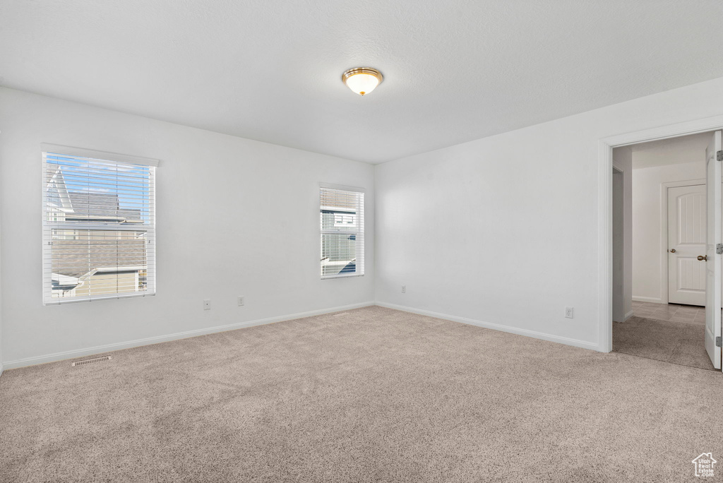 Unfurnished room featuring plenty of natural light and carpet floors