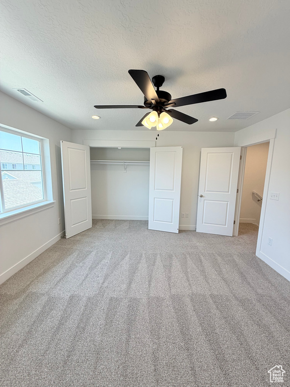 Unfurnished bedroom featuring carpet, a textured ceiling, a closet, a ceiling fan, and baseboards
