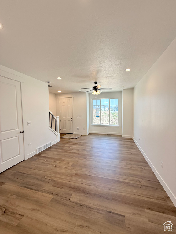 Unfurnished living room with stairway, recessed lighting, wood finished floors, a ceiling fan, and baseboards