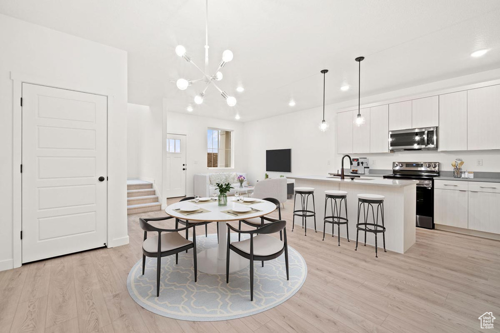 Dining room with recessed lighting, an inviting chandelier, light wood-type flooring, and stairs