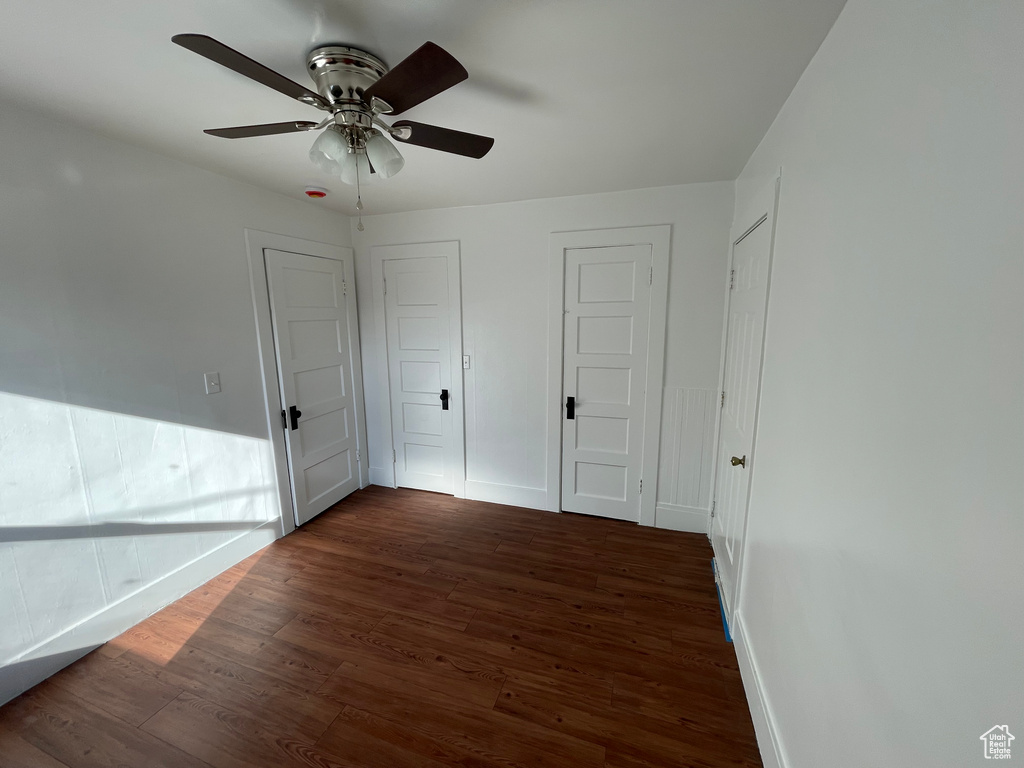 Unfurnished bedroom with ceiling fan and dark hardwood / wood-style floors