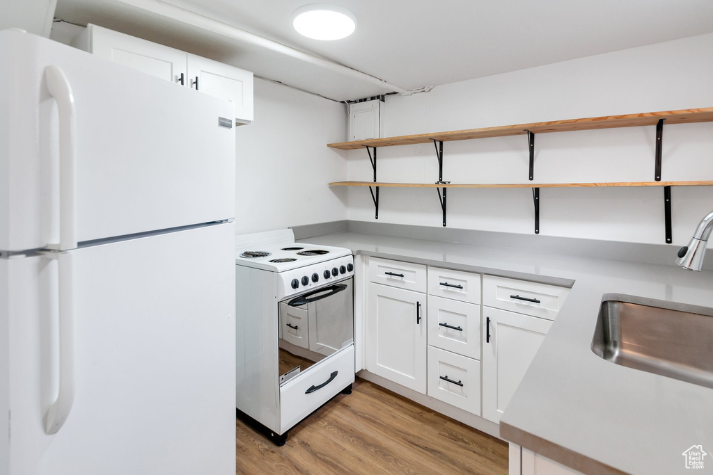 Kitchen featuring white cabinets, white appliances, light hardwood / wood-style floors, and sink