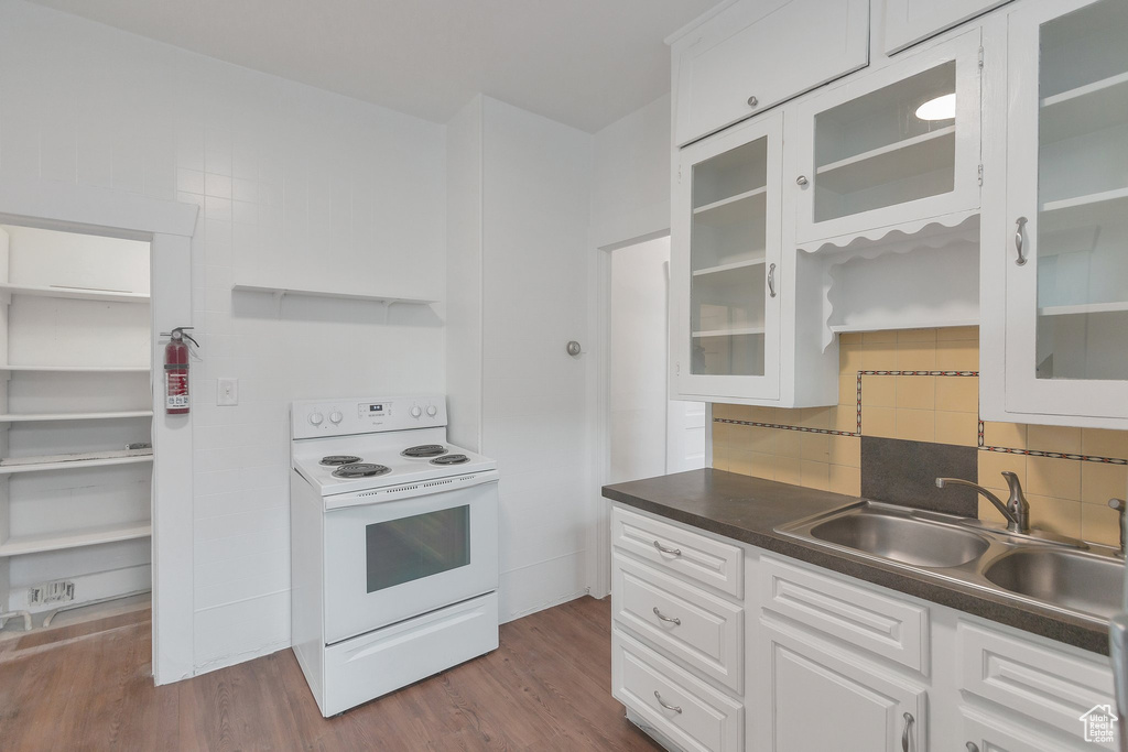 Kitchen featuring dark hardwood / wood-style flooring, sink, white electric range oven, white cabinetry, and decorative backsplash