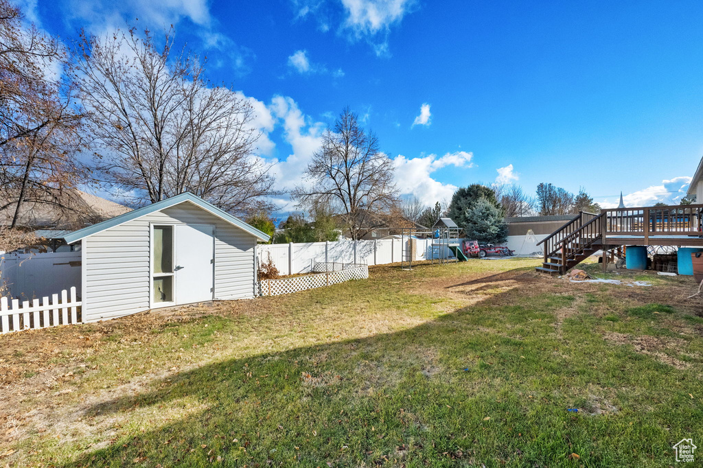 View of yard featuring a playground, a wooden deck, and a shed