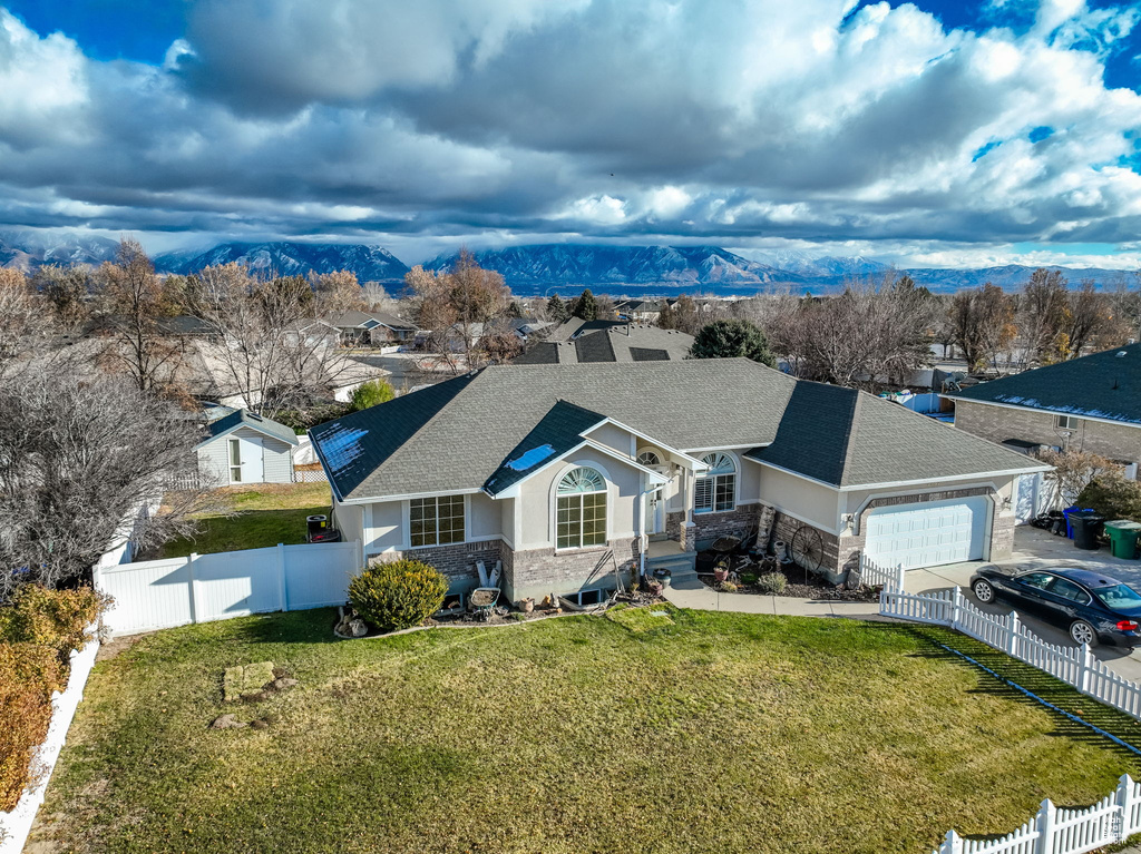 View of front of house featuring a mountain view, a front yard, and a garage