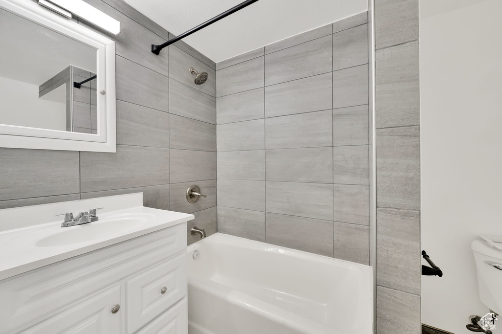 Full bathroom with toilet, vanity, tile walls, and tiled shower / bath