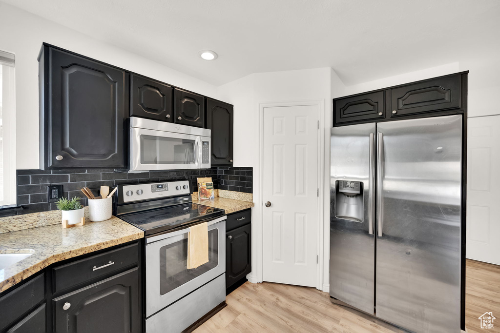 Kitchen featuring decorative backsplash, stainless steel appliances, and light hardwood / wood-style floors