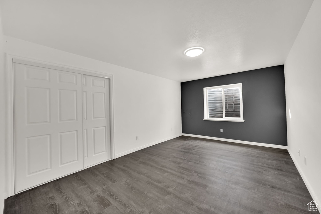 Unfurnished bedroom featuring dark hardwood / wood-style flooring and a closet