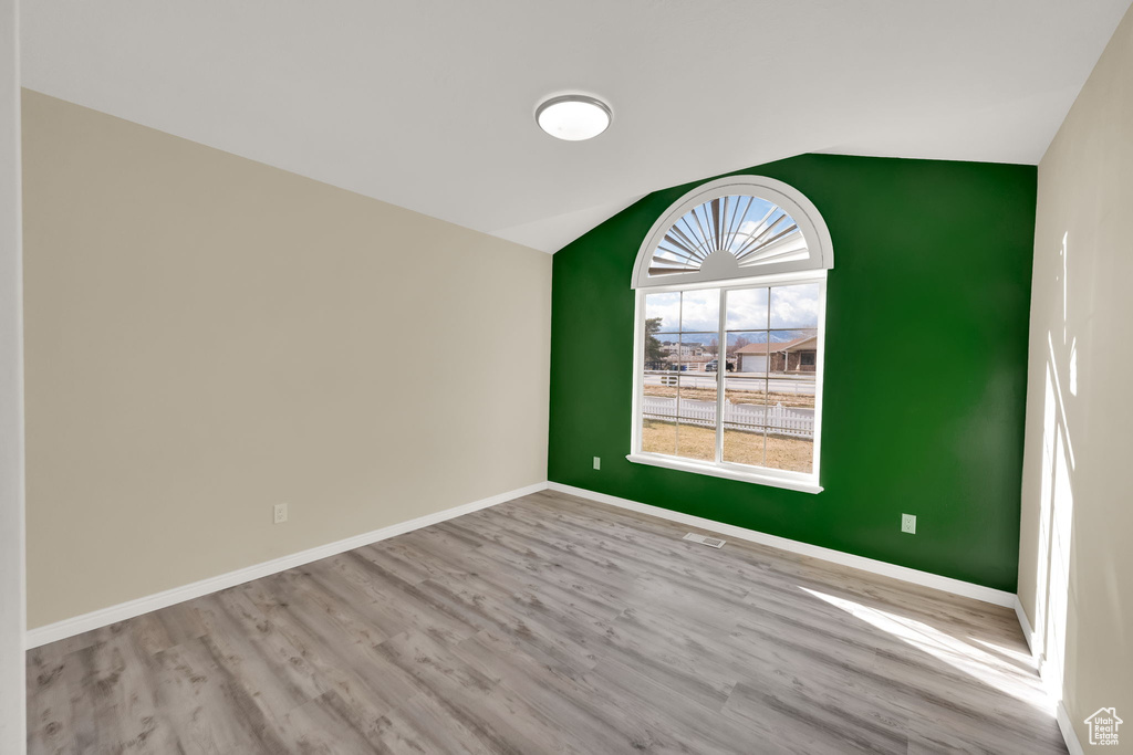 Spare room featuring light hardwood / wood-style floors and lofted ceiling