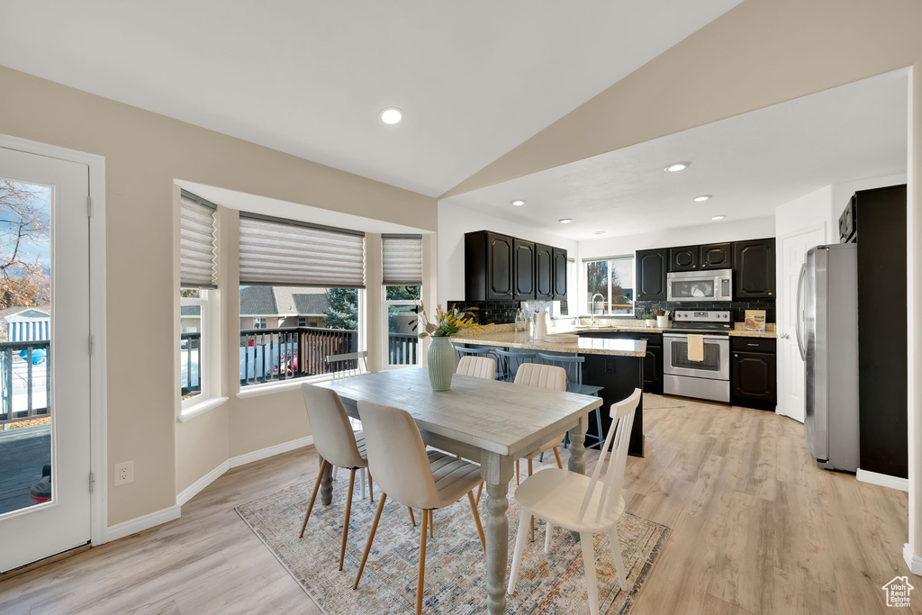 Dining area featuring light hardwood / wood-style floors, lofted ceiling, and sink