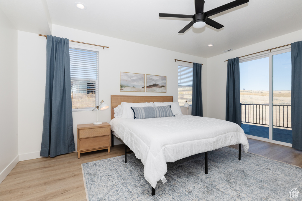Bedroom with ceiling fan, light hardwood / wood-style flooring, and multiple windows