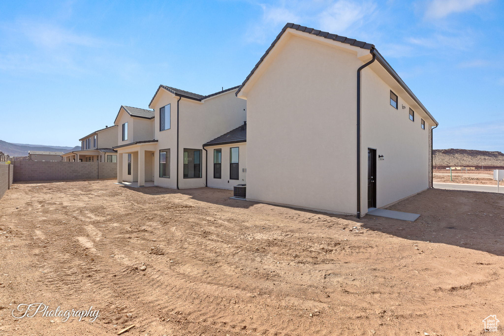 Rear view of house with a fenced backyard, stucco siding, a tiled roof, and central AC