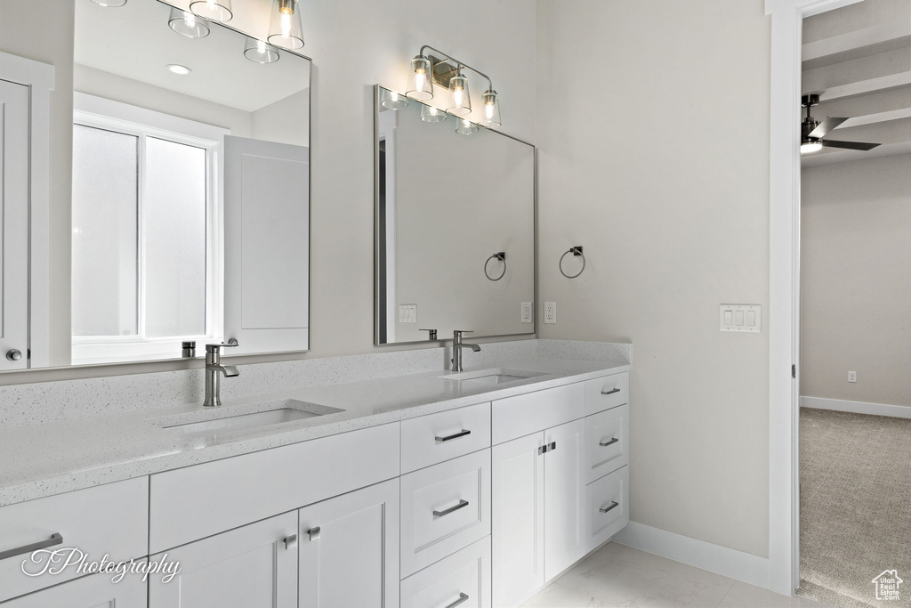 Bathroom with baseboards, a ceiling fan, double vanity, and marble finish flooring