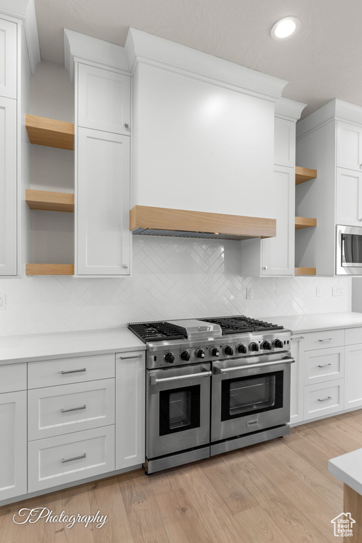 Kitchen featuring open shelves, stainless steel appliances, light countertops, tasteful backsplash, and recessed lighting