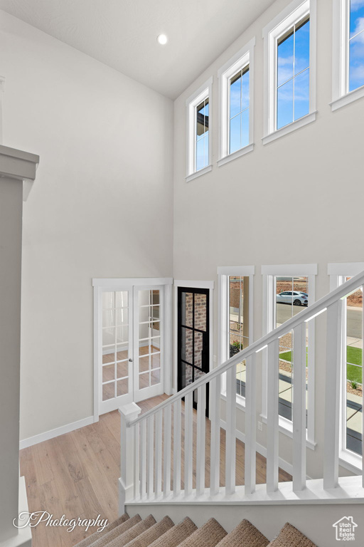 Stairs featuring wood finished floors, a towering ceiling, baseboards, and recessed lighting