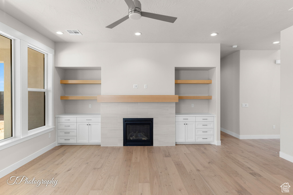Unfurnished living room featuring baseboards, light wood-type flooring, a ceiling fan, a fireplace, and recessed lighting
