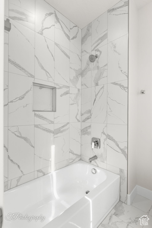 Full bathroom featuring shower / bath combination, marble look tiles, and baseboards