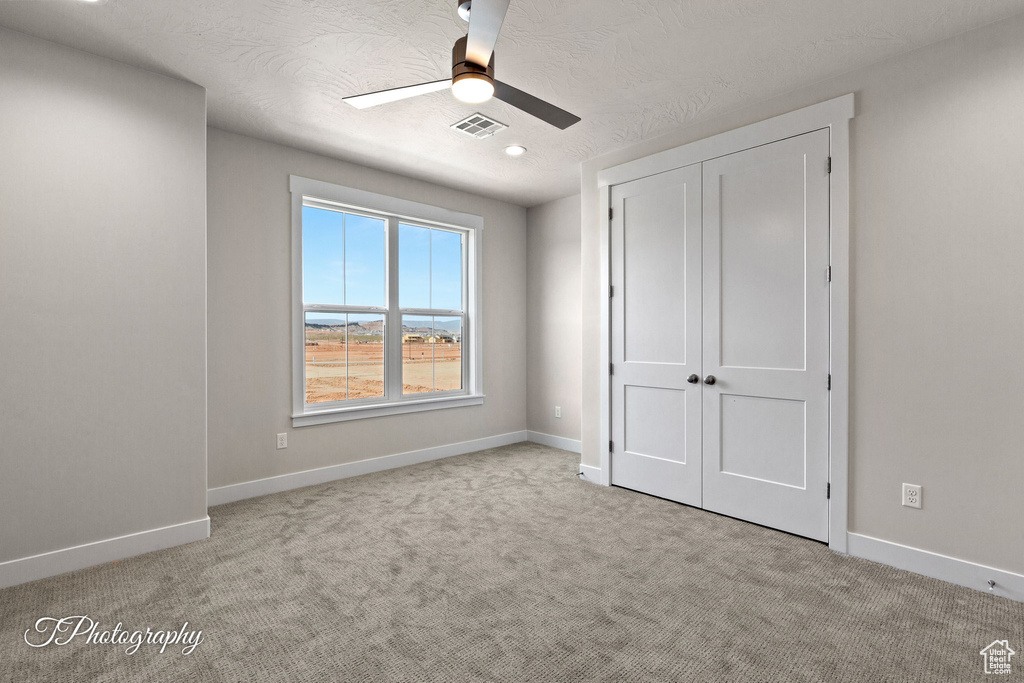 Unfurnished bedroom with carpet flooring, baseboards, a closet, and a textured ceiling