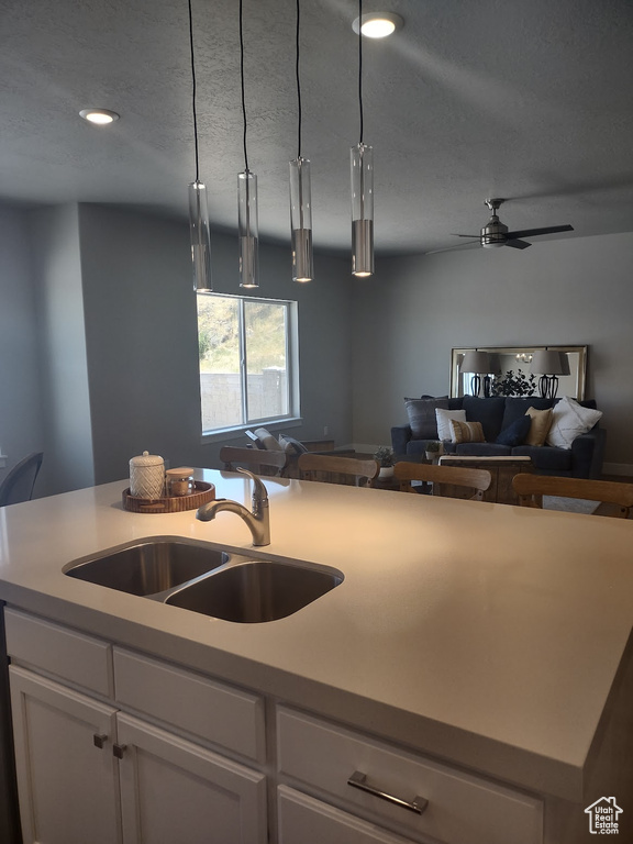 Kitchen with open floor plan, white cabinetry, a ceiling fan, a textured ceiling, and light countertops
