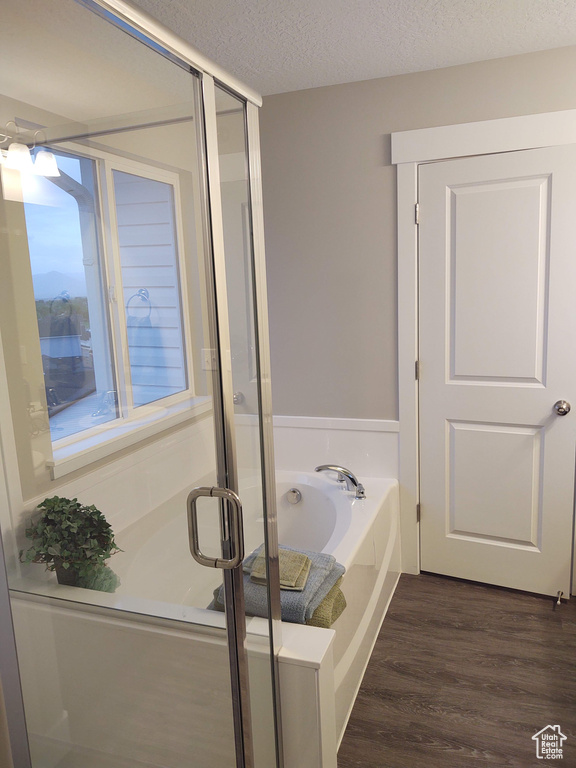 Bathroom featuring wood-type flooring, a textured ceiling, and shower with separate bathtub