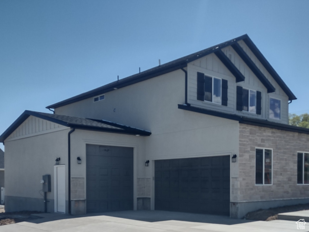 View of property exterior featuring stone siding, driveway, and a garage