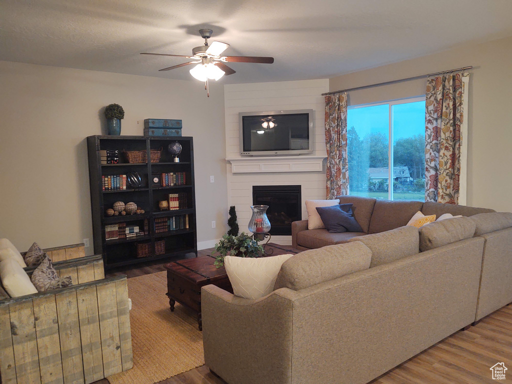 Living room featuring hardwood / wood-style floors, a large fireplace, and ceiling fan