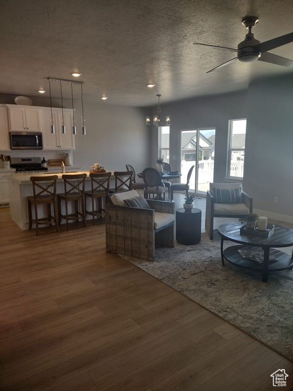 Living area with dark wood-type flooring, ceiling fan, recessed lighting, and a chandelier