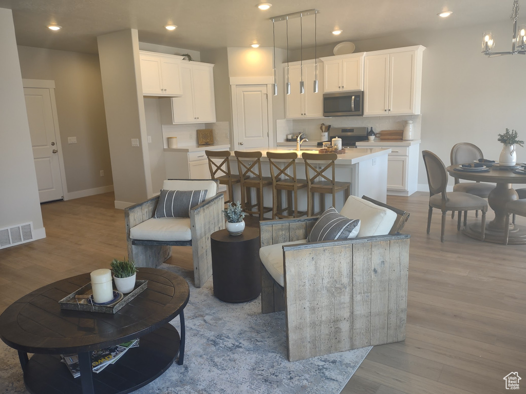 Living room featuring wood finished floors, a chandelier, and recessed lighting