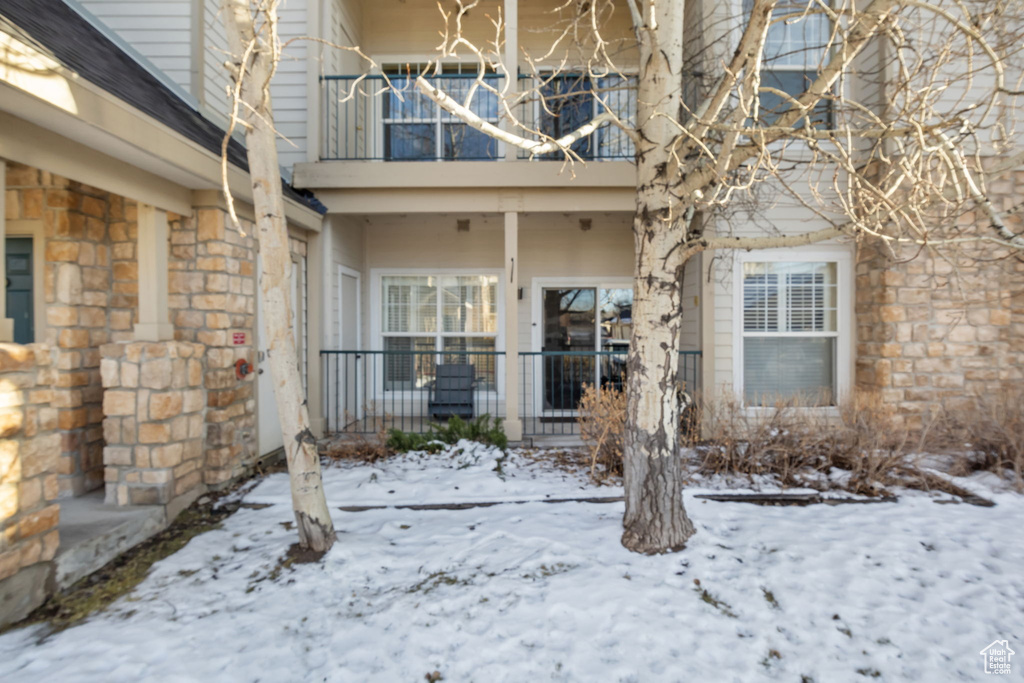 Snow covered property entrance with a balcony