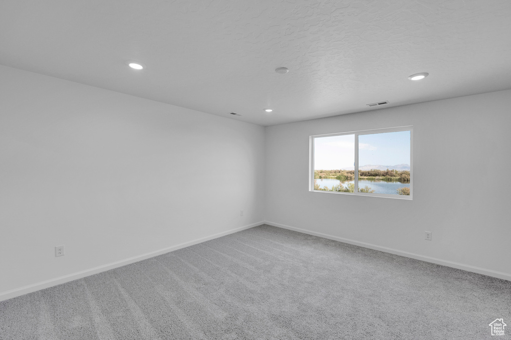 Carpeted spare room with recessed lighting, baseboards, and a water view