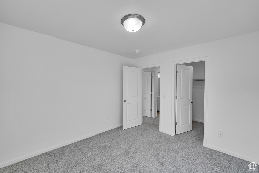 Unfurnished bedroom featuring carpet, baseboards, and a walk in closet