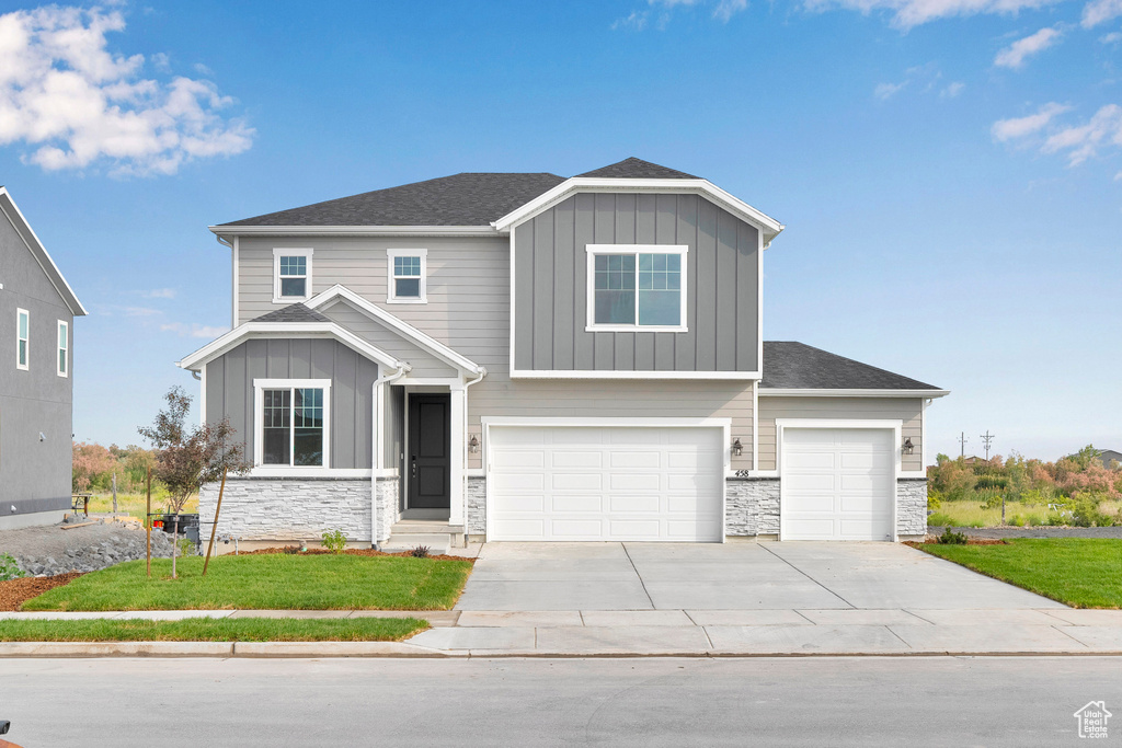 Craftsman-style house with board and batten siding, stone siding, and driveway