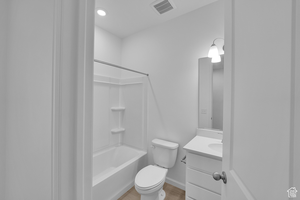 Bathroom with vanity, toilet, shower / bath combination, baseboards, and wood finished floors