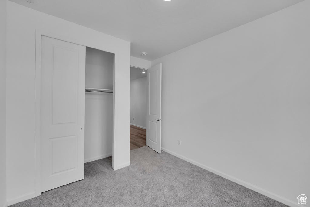 Unfurnished bedroom with carpet floors, a closet, and baseboards