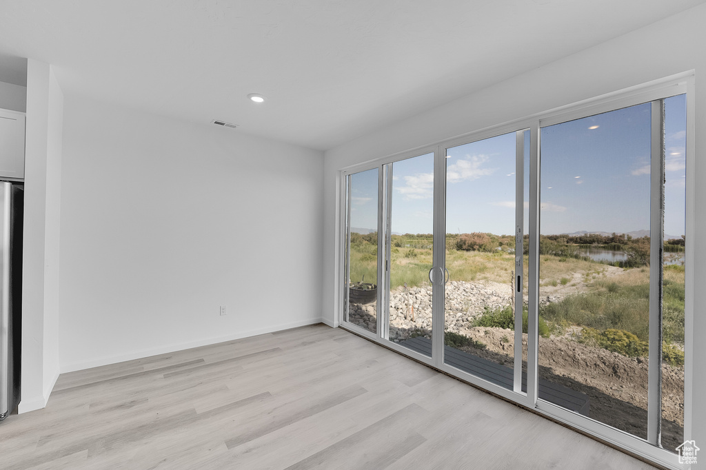 Empty room featuring light wood-style flooring, a water view, recessed lighting, and baseboards
