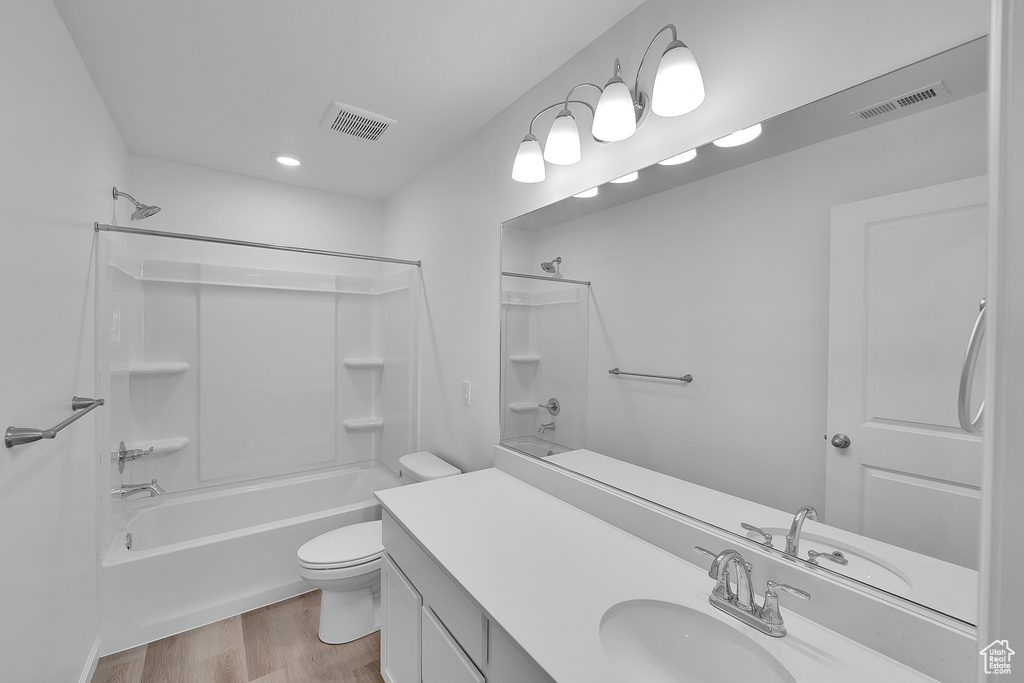 Bathroom with toilet, vanity, shower / washtub combination, wood finished floors, and recessed lighting